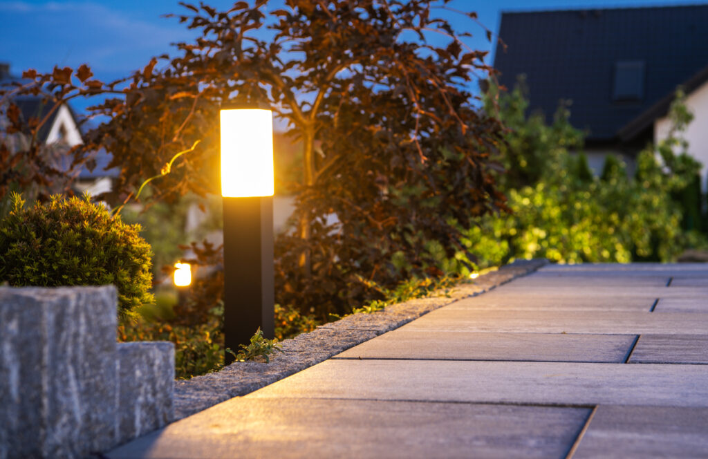 Closeup of Garden Bollard Lamp Installed Along the Walkway in Landscaped Backyard Garden. Evening Time. Outdoor Lighting Theme.